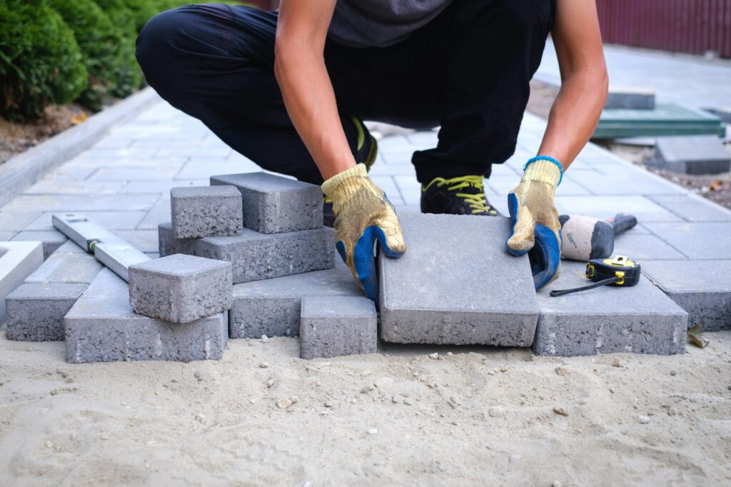 The master in yellow gloves lays paving stones